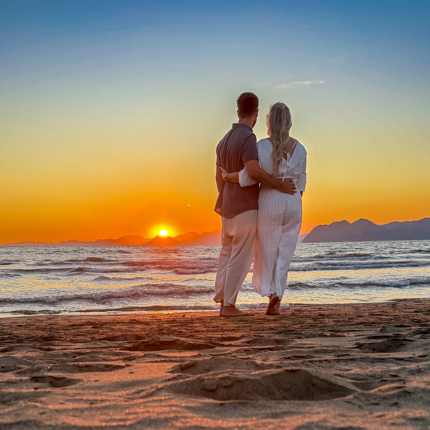 Katha und Bennet Arm in Arm am Strand im Sonnenuntergang